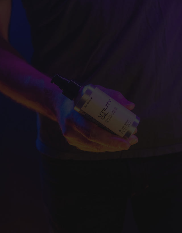 Beardbrand Utility Oil in a person's hands highlighted in vibrant lighting