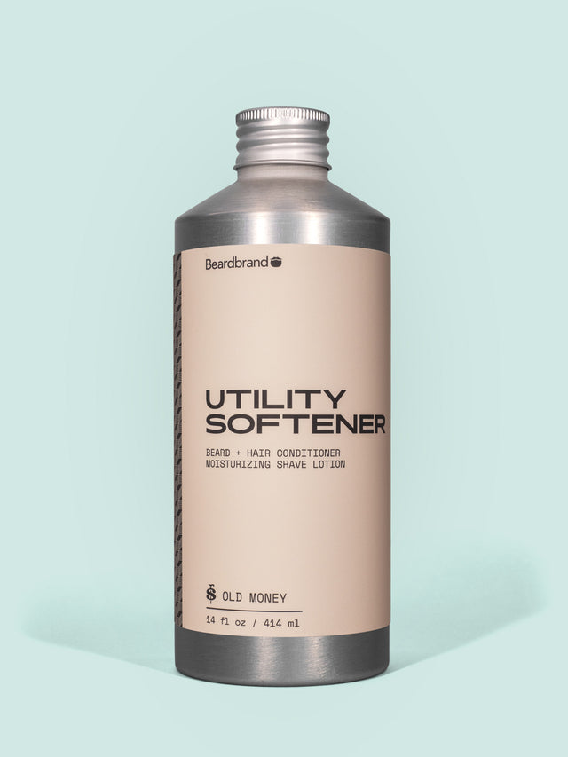 Beardbrand Utility Softener in Aluminum packaging with a screw cap against a light blue background.